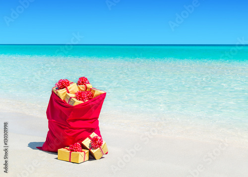 Christmas sack full of wrapped gift boxes at tropical beach