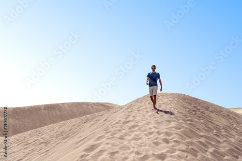 Man walking in desert dunes with sunglases