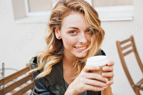 Young woman wearing casual outfit drinks coffee at cafe terrace