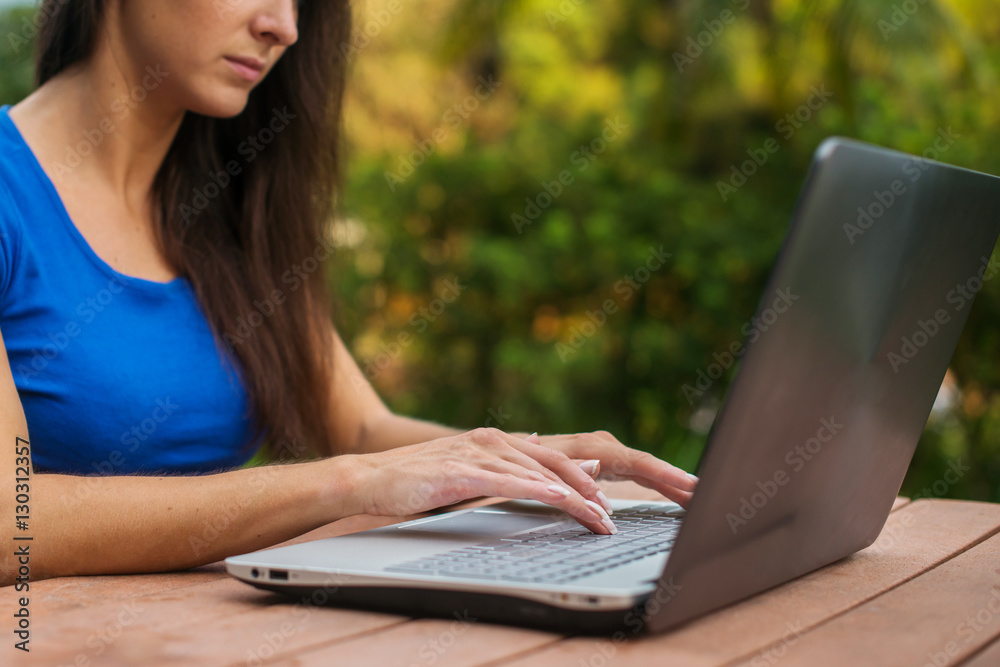 Close-up view of female hands on laptop keyboard. Student learning outdoors. Close-up view of female hands on laptop keyboard. Student learning outdoors.