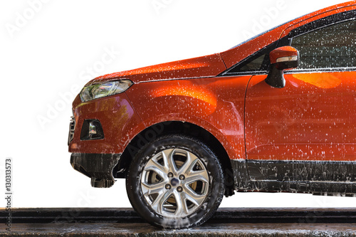 Billede på lærred Orange car with white soap on the body in car care shop