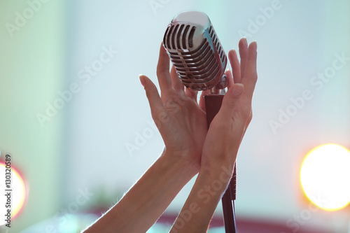 Female hands holding retro microphone, close up