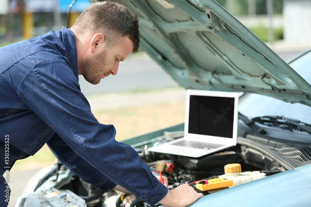Mechanic using computer diagnostics while repairing car Mechanic using computer diagnostics while repairing car