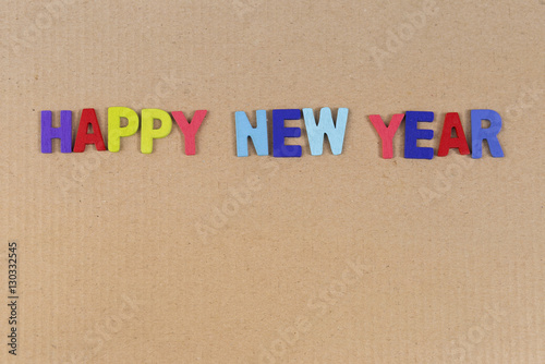 Colorful Happy new year wooden text on brown cardboard background