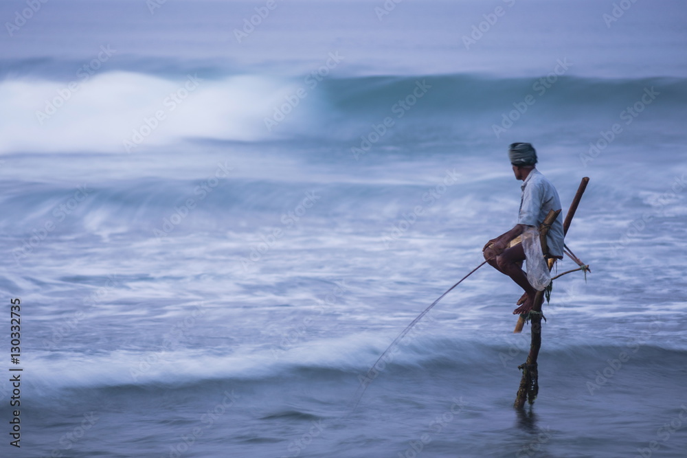 Stilt fishing, a stilt fisherman in the waves at Midigama near Weligama, South Coast, Sri Lanka Stilt fishing, a stilt fisherman in the waves at Midigama near Weligama, South Coast, Sri Lanka