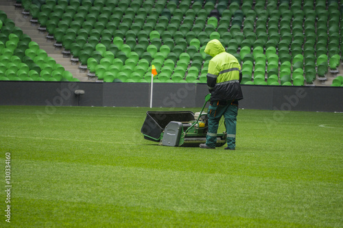 Soccer and football field, seating rows in a stadium. Man mows the grass. World Cup.