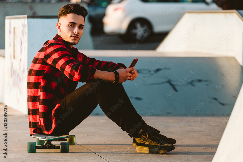 Man sitting on longboard and using smartphone Man sitting on longboard and using smartphone