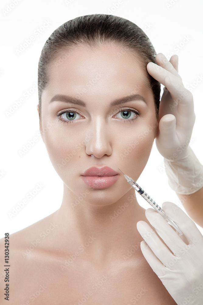 Beauty woman portrait close up on white background with hands in medical gloves on face making injection.