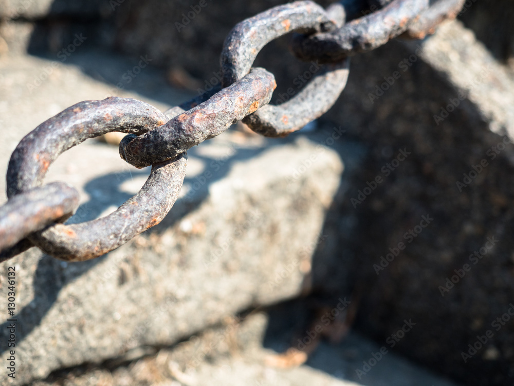 Picture of the selective focus on a rusty iron chain against the blurred background of the gray stones. Rusty iron chain close up. Picture of the selective focus on a rusty iron chain against the blurred background of the gray stones. Rusty iron chain close up.