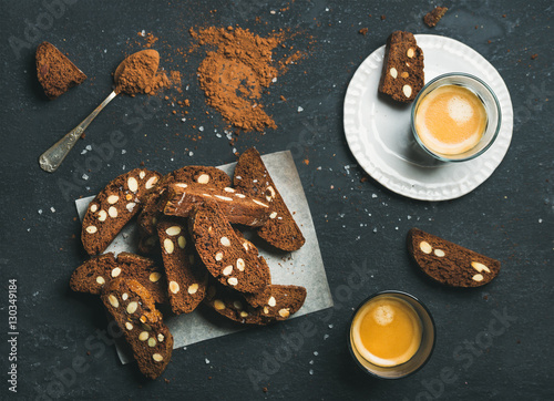 Dark chocolate and sea salt Biscotti with almonds and two glasses of coffee espresso over dark stone background, top view, selective focus, horizontal composition