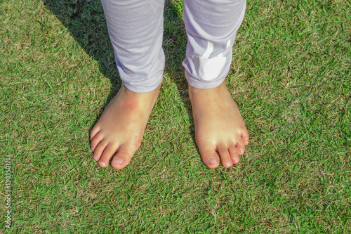 Child foot on the green grass