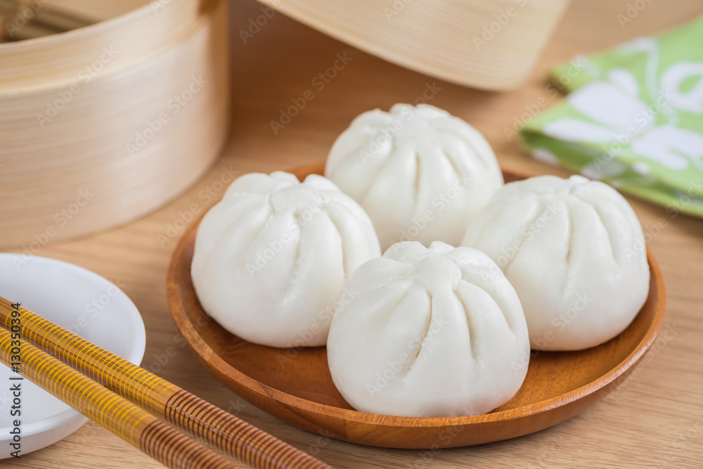 Steamed buns on wooden plate and bamboo steamer basket Steamed buns on wooden plate and bamboo steamer basket