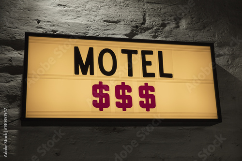 Close-up of Motel and dollar signs signboard against gray wall