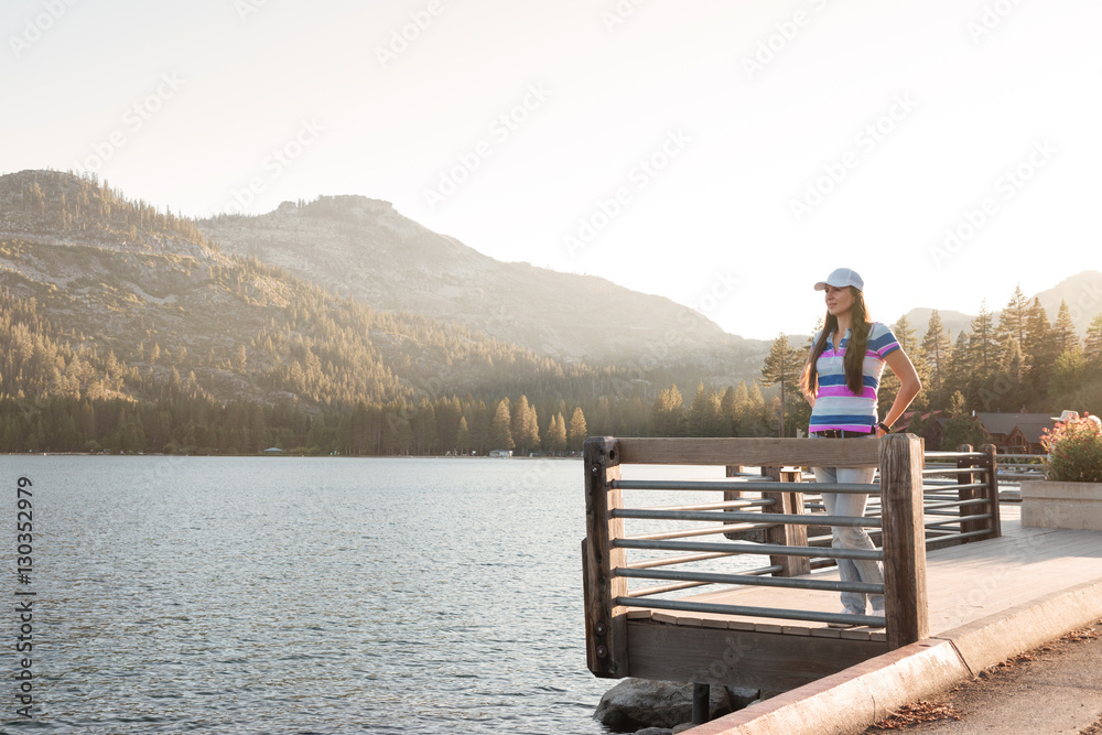 Young woman standing on a wooden lake pier