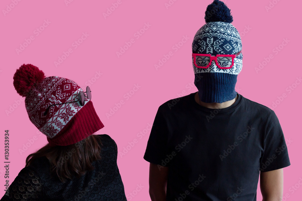 Young hipster couple fashion portrait; Wearing christmas hats as robber masks with bright glasses. Millennial idea of costume creative party in tumbler crazy style on abstract minimal pink background. - obrazy, fototapety, plakaty 