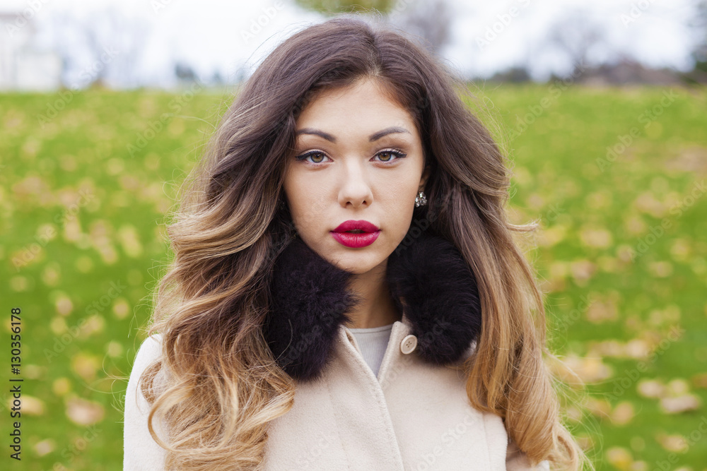 Naklejka premium Portrait of a young beautiful woman in beige coat