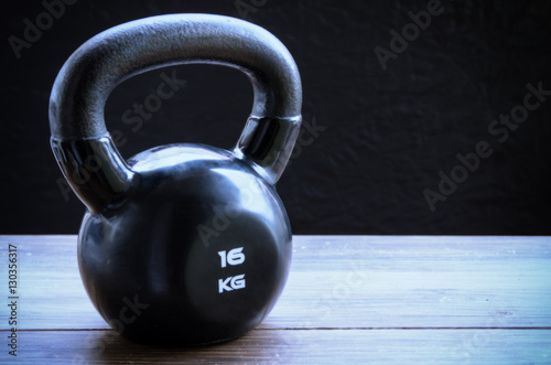 Black kettlebell on wooden background with copyspace. Concept for sport and gym.