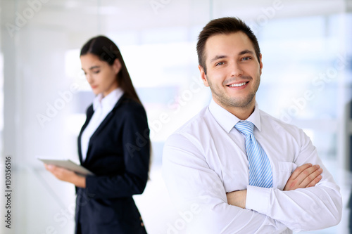 Smiling businessman  in office with colleagues in the background