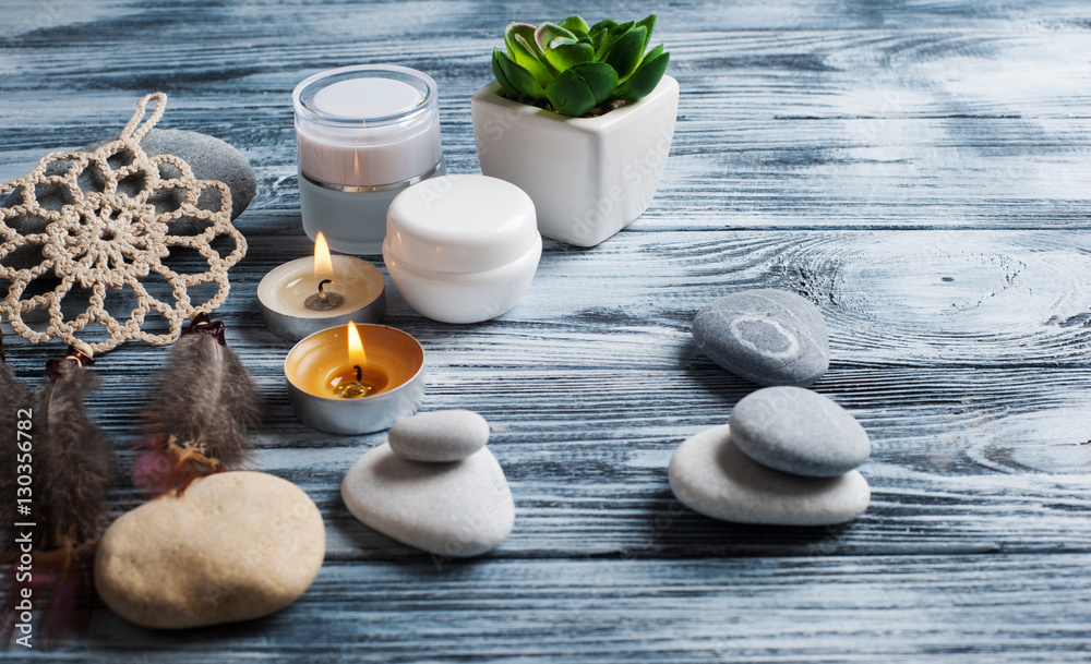 Spa background with cosmetics bottles, stones and lit candles Spa background with cosmetics bottles, stones and lit candles