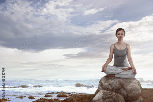 Portrait of asian woman sitting over the rock doing yoga