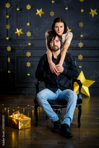 Young woman embraces man sitting in a chair. photo