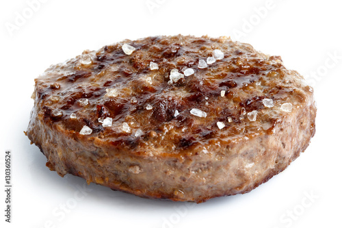 Single grilled hamburger patty with salt isolated on white.