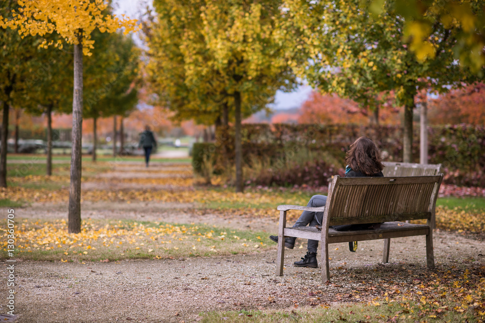 Ragazza di spalle seduta su una panchina in un parco