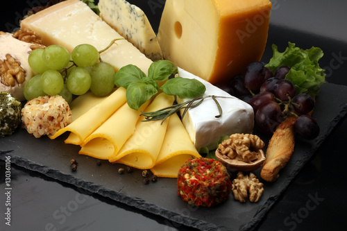Cheese platter with different cheese and grapes - some emmental, gauda, parmesan and brie  cheese on a table for brunch photo