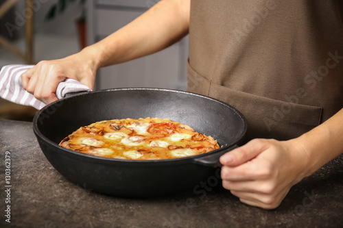 Woman holding freshly baked pizza in a pan