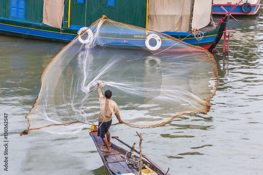 Fisherman casting net along the Mekong River in the capital city