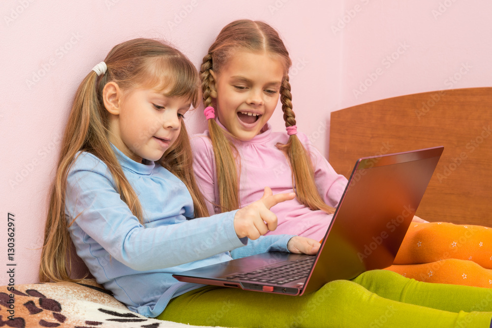 Two girls include laptop at work, sitting on the bed Two girls include laptop at work, sitting on the bed