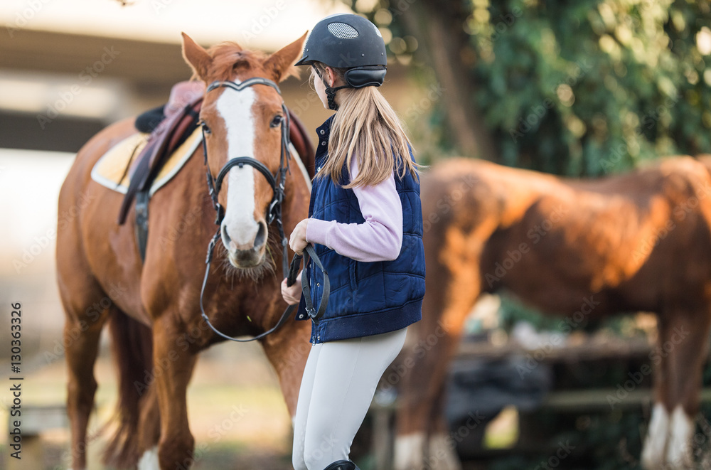 Obraz premium Young girl preparing horse for ride