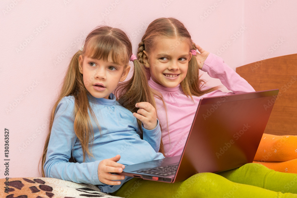 Two girls were distracted from the laptop and looked toward Two girls were distracted from the laptop and looked toward