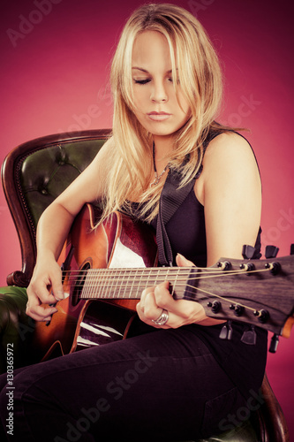 Blond woman sitting and playing guitar