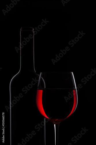 Rotweinflasche und Rotweinglas vor dunklem Hintergrund