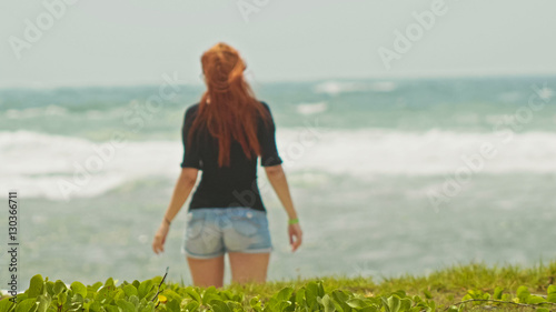 Young woman with long red hair on caribbean beach, Dominican Republic, rear view