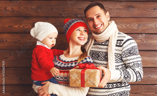 happy family mother, father and baby with Christmas gifts on woo