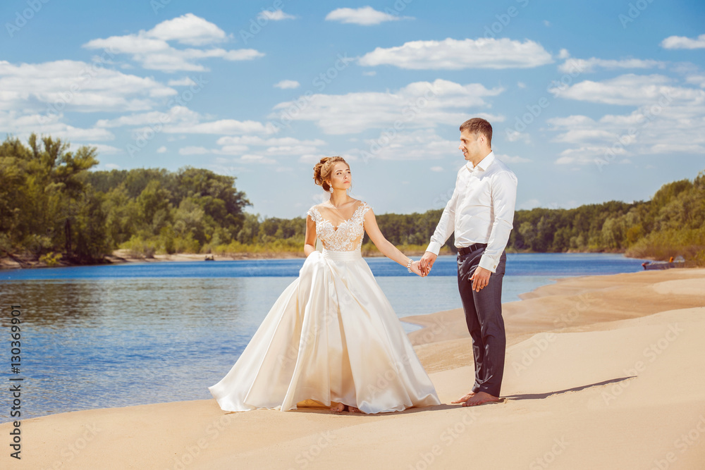 Beautiful wedding couple is walking along beach at honeymoon Beautiful wedding couple is walking along beach at honeymoon