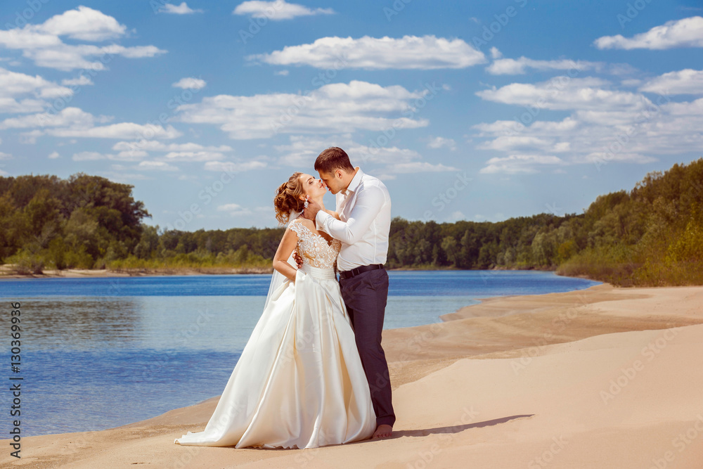 Beautiful wedding couple is kissing at beach background Beautiful wedding couple is kissing at beach background