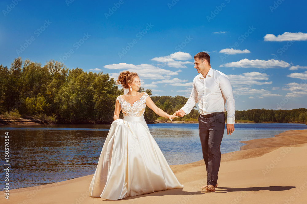 Beautiful happy wedding couple is walking along beach Beautiful happy wedding couple is walking along beach