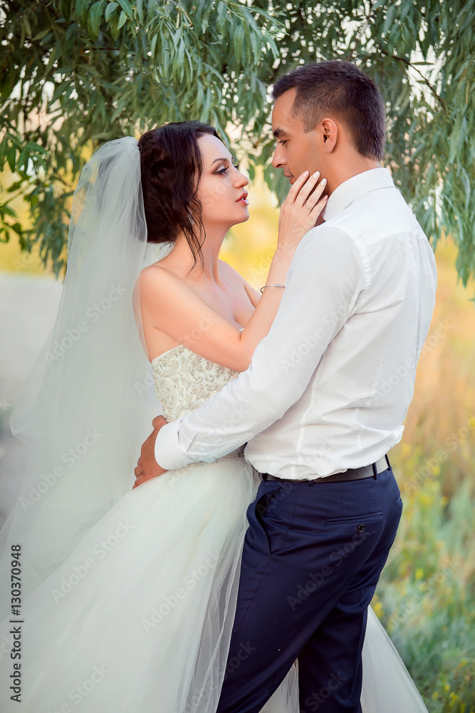 Luxury young girl in a long white dress.Man embraces her waist.Newlyweds, sincere feelings, a holiday for two, a wedding in European style. Fantastic shooting. Fashionable toning. Creative color.
