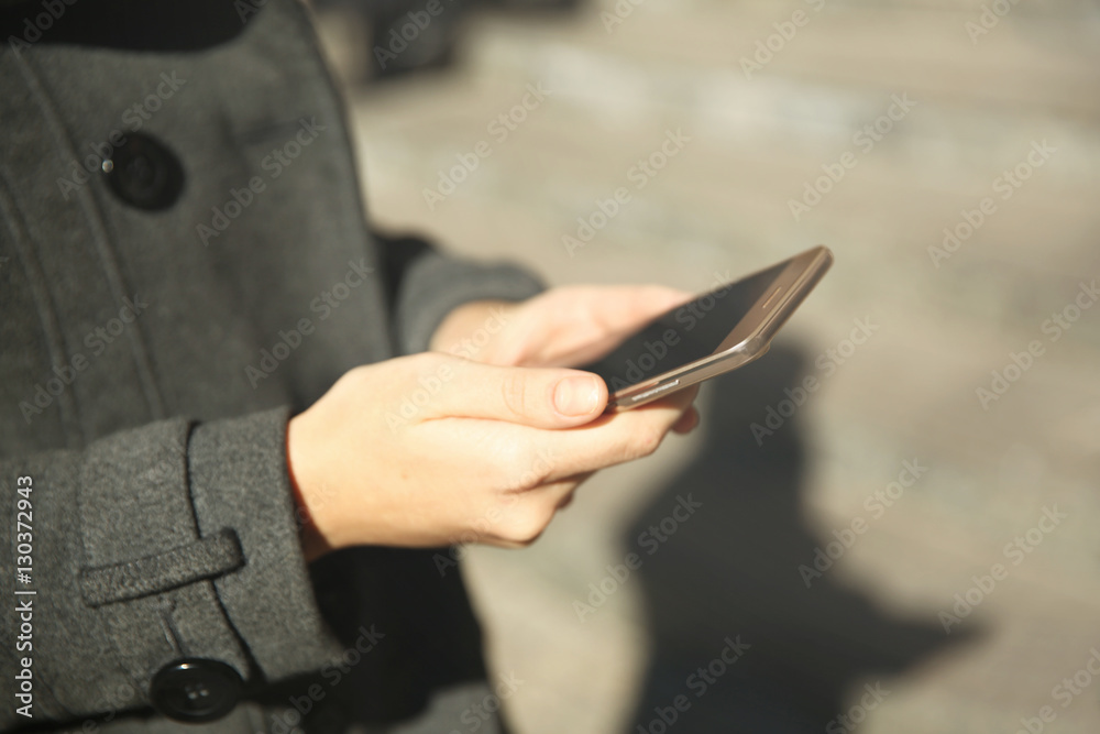 Woman holding modern cellphone, outdoor