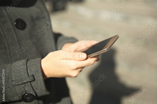 Woman holding modern cellphone, outdoor