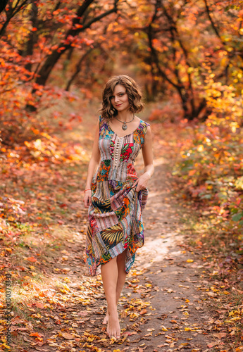 Luxury lady in a colorful dress.Nice smile, playful gait. Long beautiful legs. Fabulous Golden autumnal.Picturesque nature.Fantastic shooting.Fashionable toning.Creative color. © kharchenkoirina