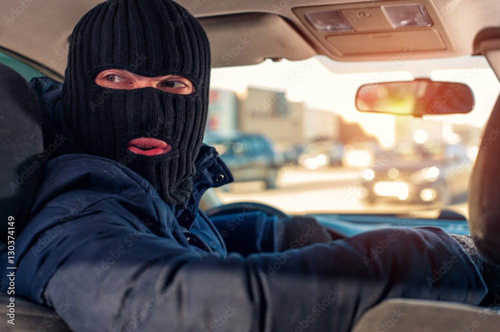 Car thief in black robbery mask driving auto Car thief in black robbery mask driving auto