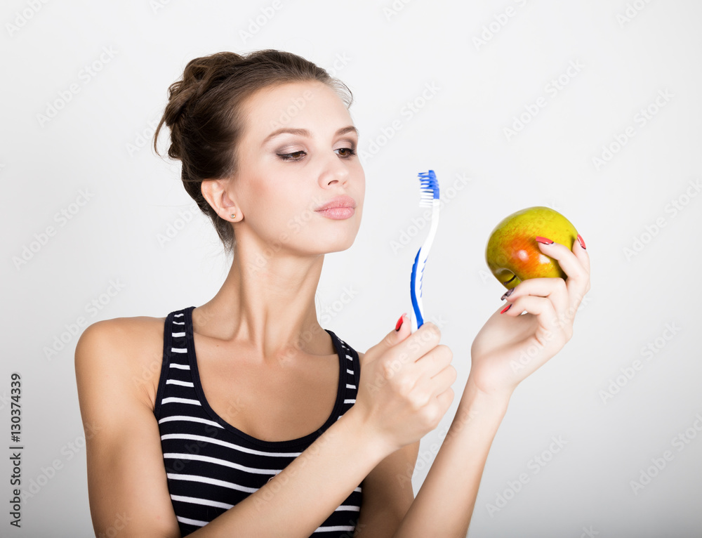 Portrait of young woman holding an apple and toothbrush, dental health concept Portrait of young woman holding an apple and toothbrush, dental health concept