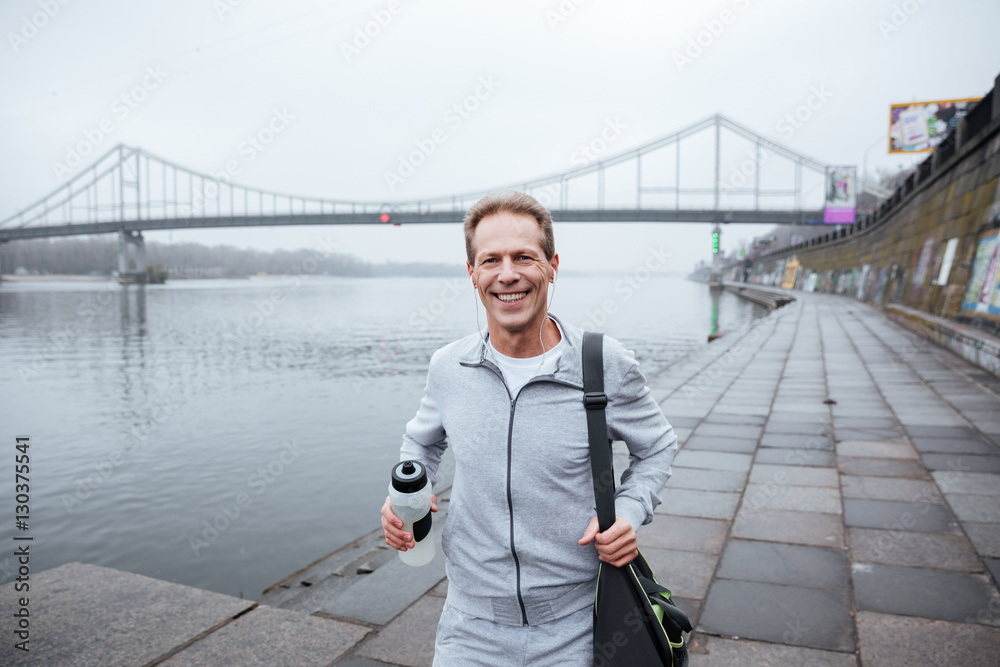 Runner with water and bag near the river Runner with water and bag near the river