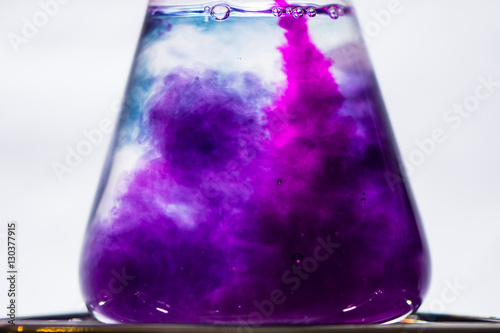 Initial color change in chemical chameleon reaction. Intense pink of potassium permanganate solution turns purple when poured into sucrose and sodium hydroxide in water