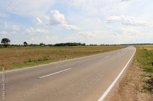 Large grass field in countryside and road