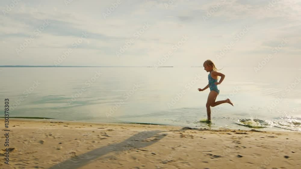 Funny girl runs along the shore, her feet touch the water and flies a lot of splashing Funny girl runs along the shore, her feet touch the water and flies a lot of splashing